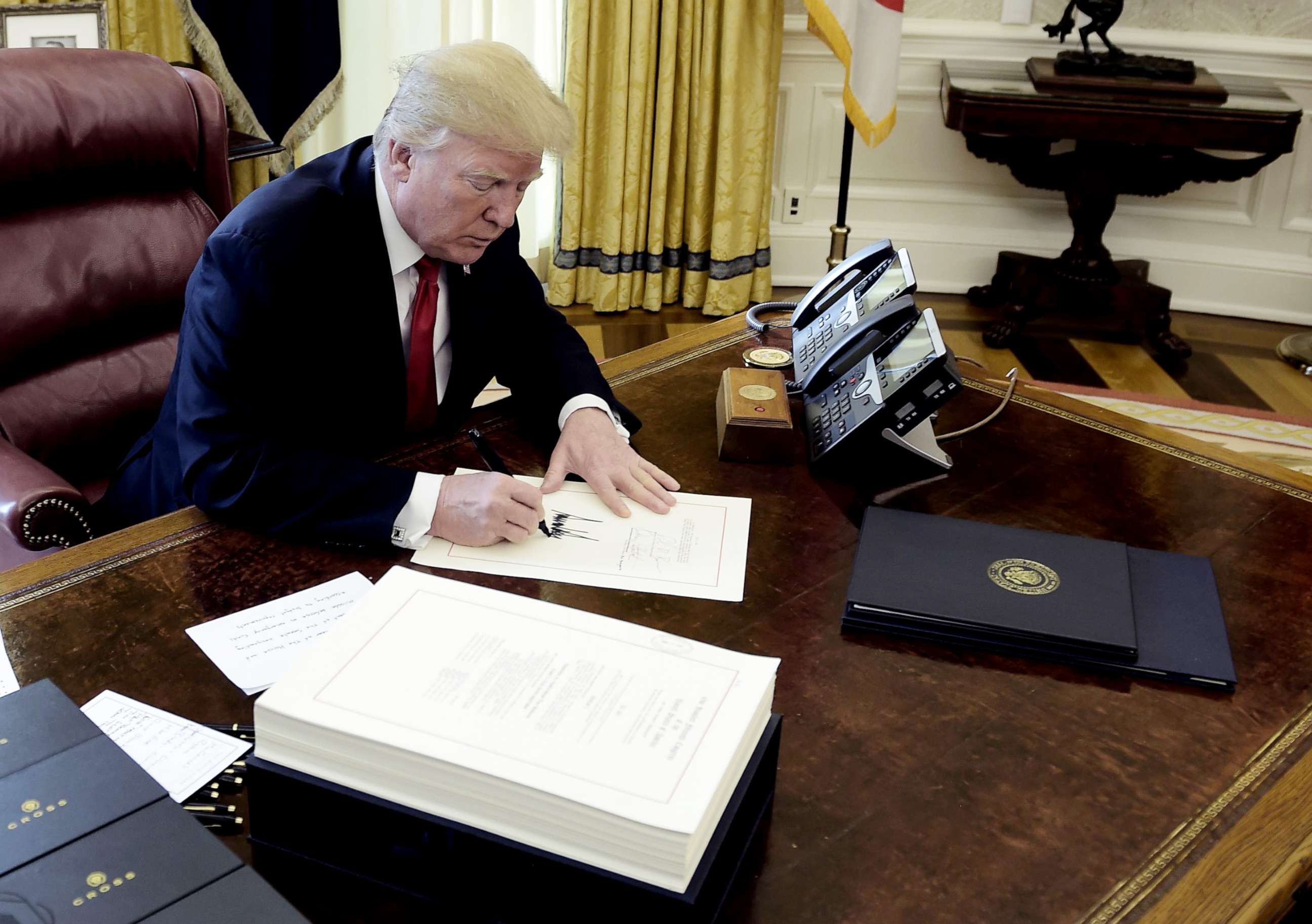 PHOTO: President Donald J. Trump signs a document during an event to sign the Tax Cut and Reform Bill in the Oval Office at The White House, Dec. 22, 2017.