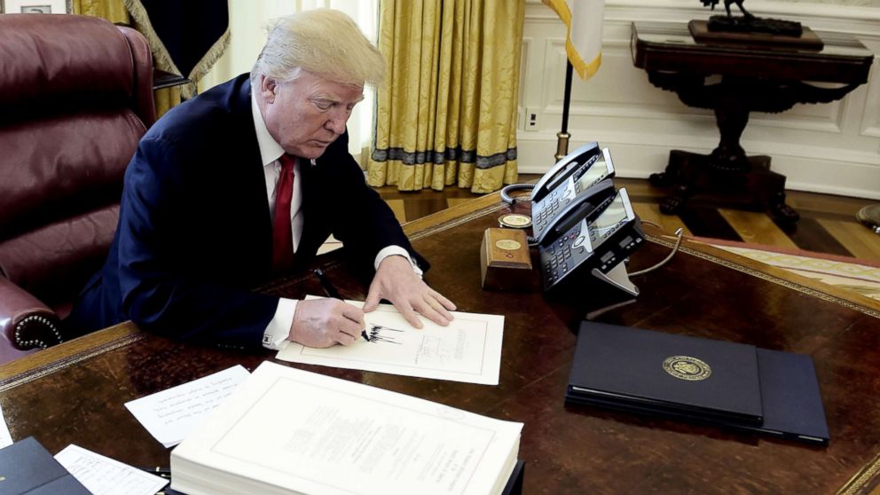 PHOTO: President Donald J. Trump signs a document during an event to sign the Tax Cut and Reform Bill in the Oval Office at The White House, Dec. 22, 2017.