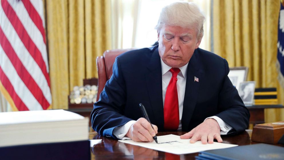 President Donald Trump signs the $1.5 trillion tax overhaul plan in the Oval Office of the White House, Dec. 22, 2017.
