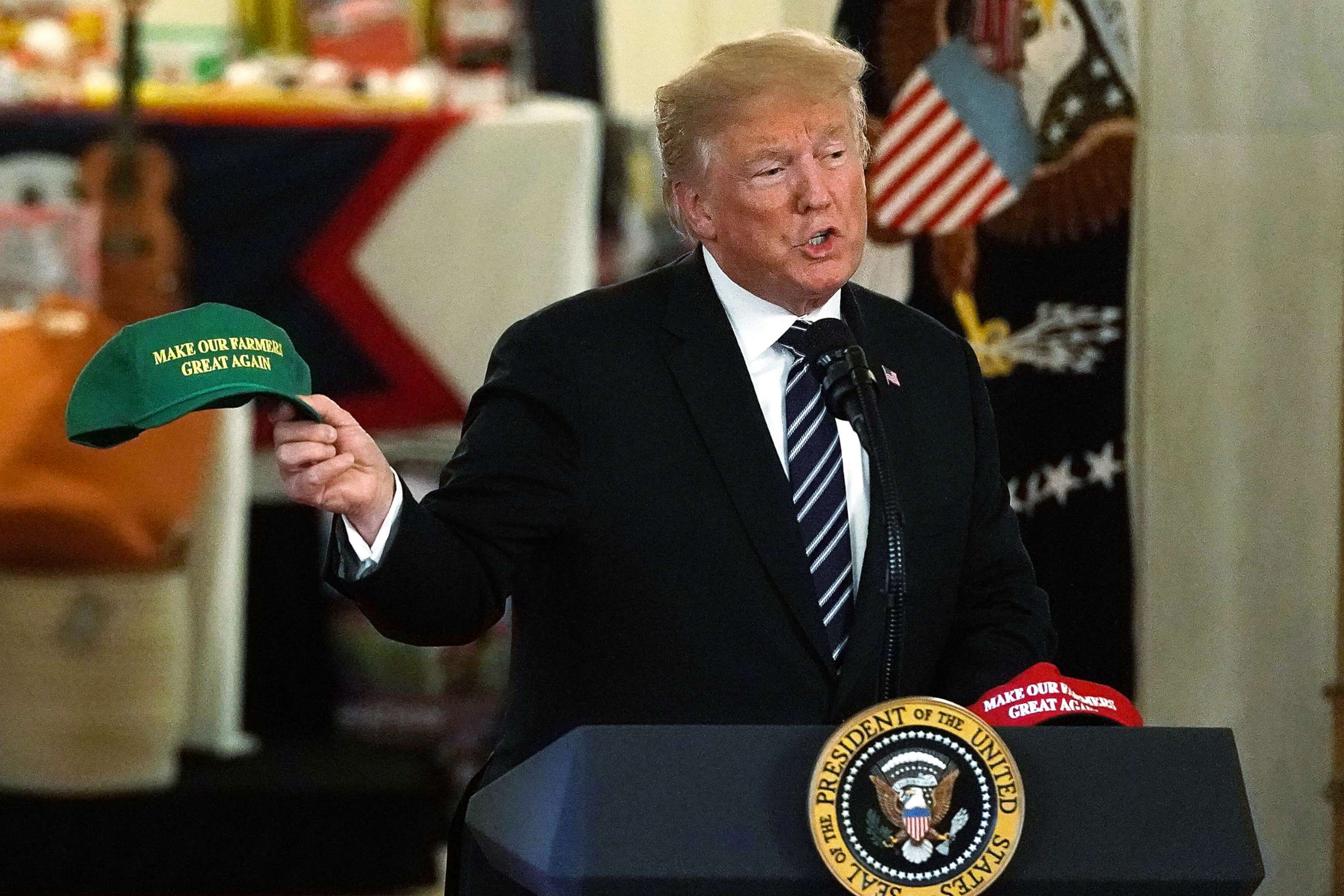 PHOTO: President Donald Trump holds up a "Make Our Farmers Great Again" hat as he speaks during the 2018 Made in America Product Showcase event July 23, 2018 at the White House in Washington. 