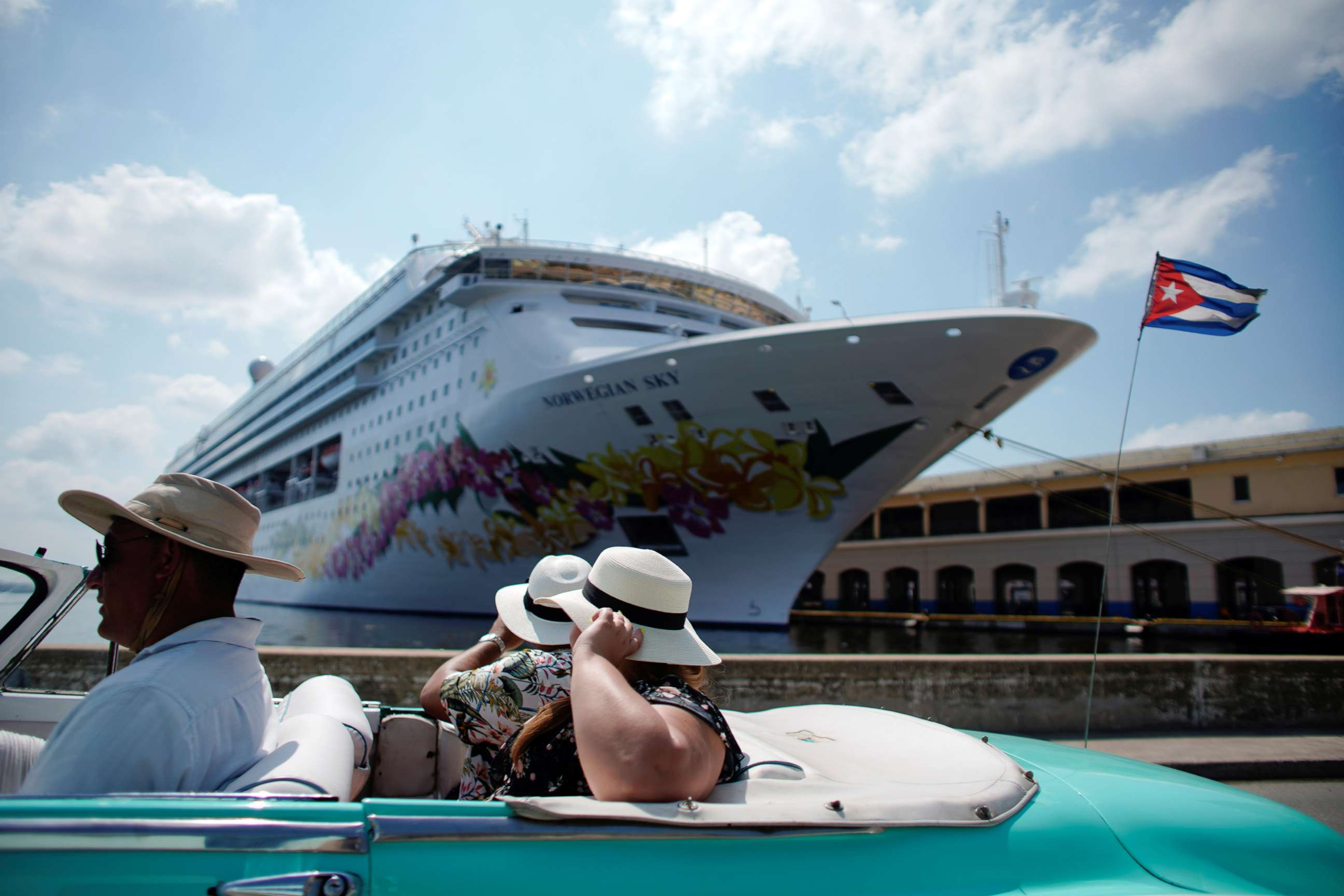 PHOTO: Tourists ride inside a vintage car as they pass by the Norwegian Sky cruise ship in Havana, Cuba, May 7, 2019.