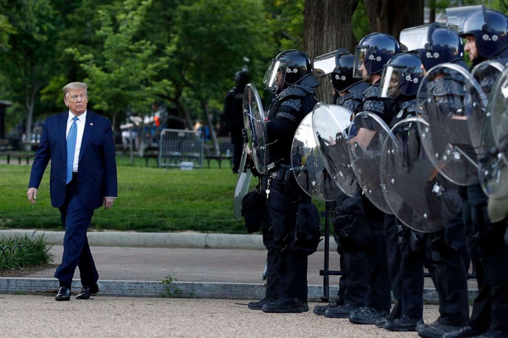 PHOTO: President Donald Trump walks past police in Lafayette Park after he walked to St. John's Church across from the White House, June 1, 2020, in Washington, D.C. Part of the church was set on fire during protests the previous night.