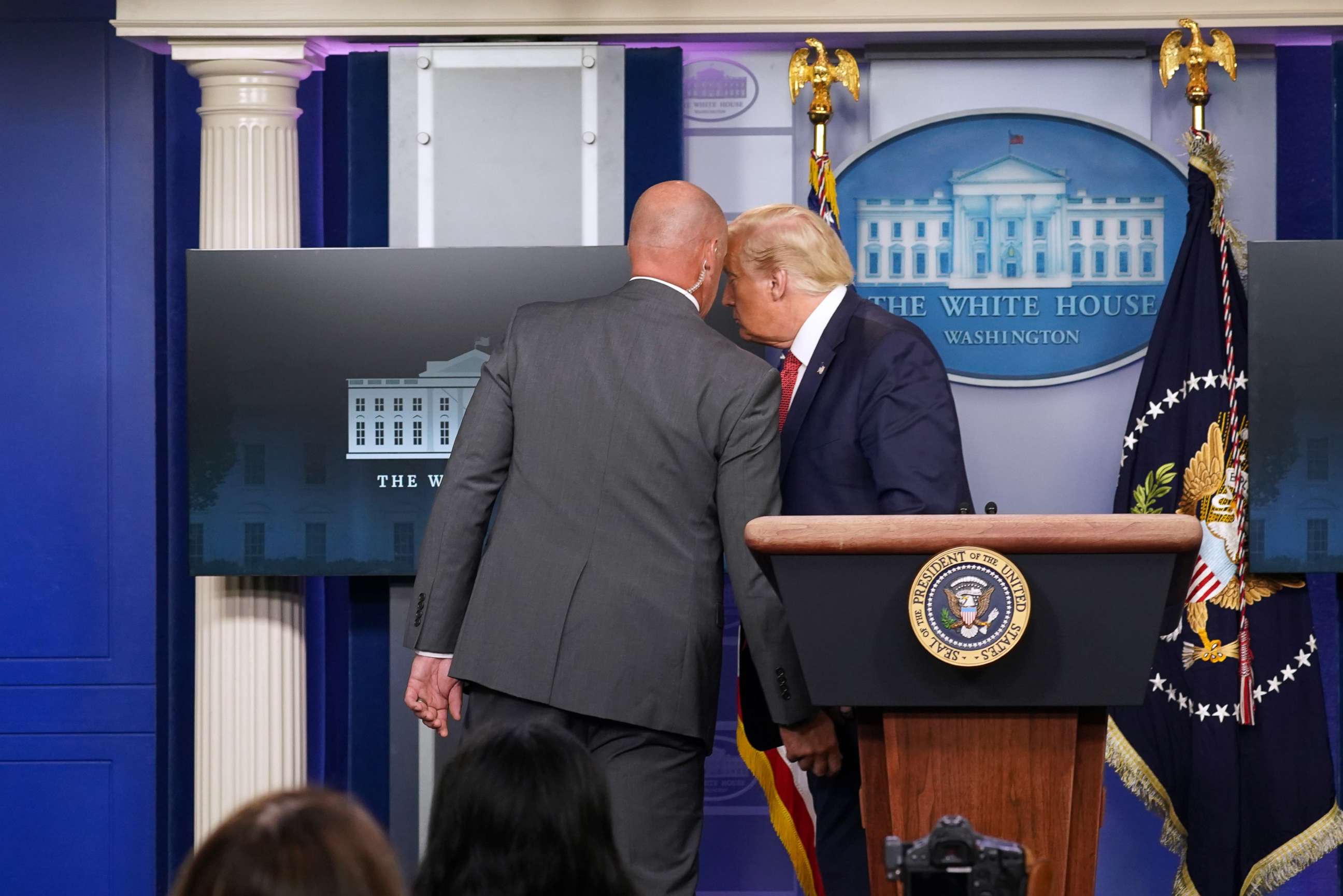 PHOTO: A member of the secret service whispers to President Donald Trump before escorting him from briefing at the White House, Aug. 10, 2020.
