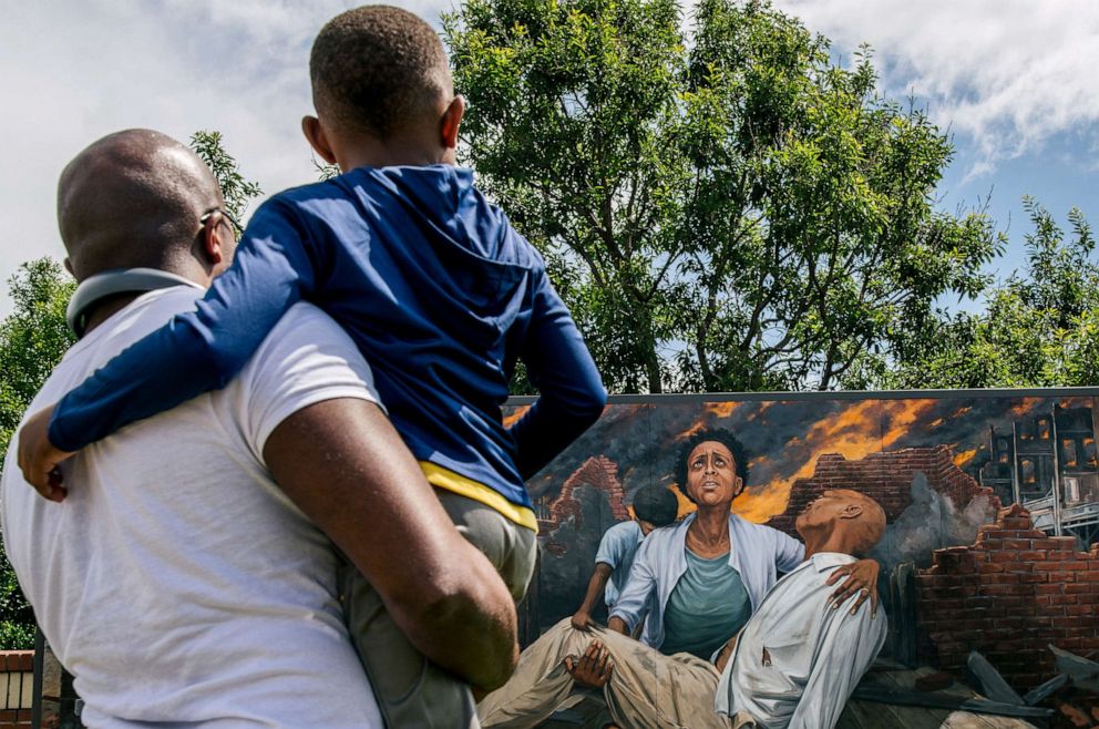 PHOTO: Nehemiah Frank teaches his cousin David McIntye II about the Tulsa massacre, in the Greenwood district of Tulsa, Okla., May 28, 2021.