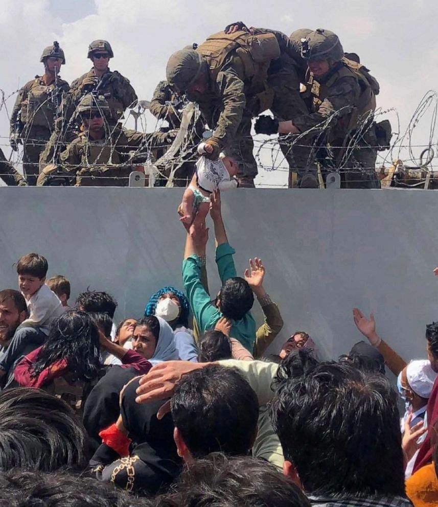 PHOTO: A U.S. Marine grabs an infant over a barbed wire fence during an evacuation at Hamid Karzai International Airport in Kabul, Afghanistan, on Aug. 19, 2021. 