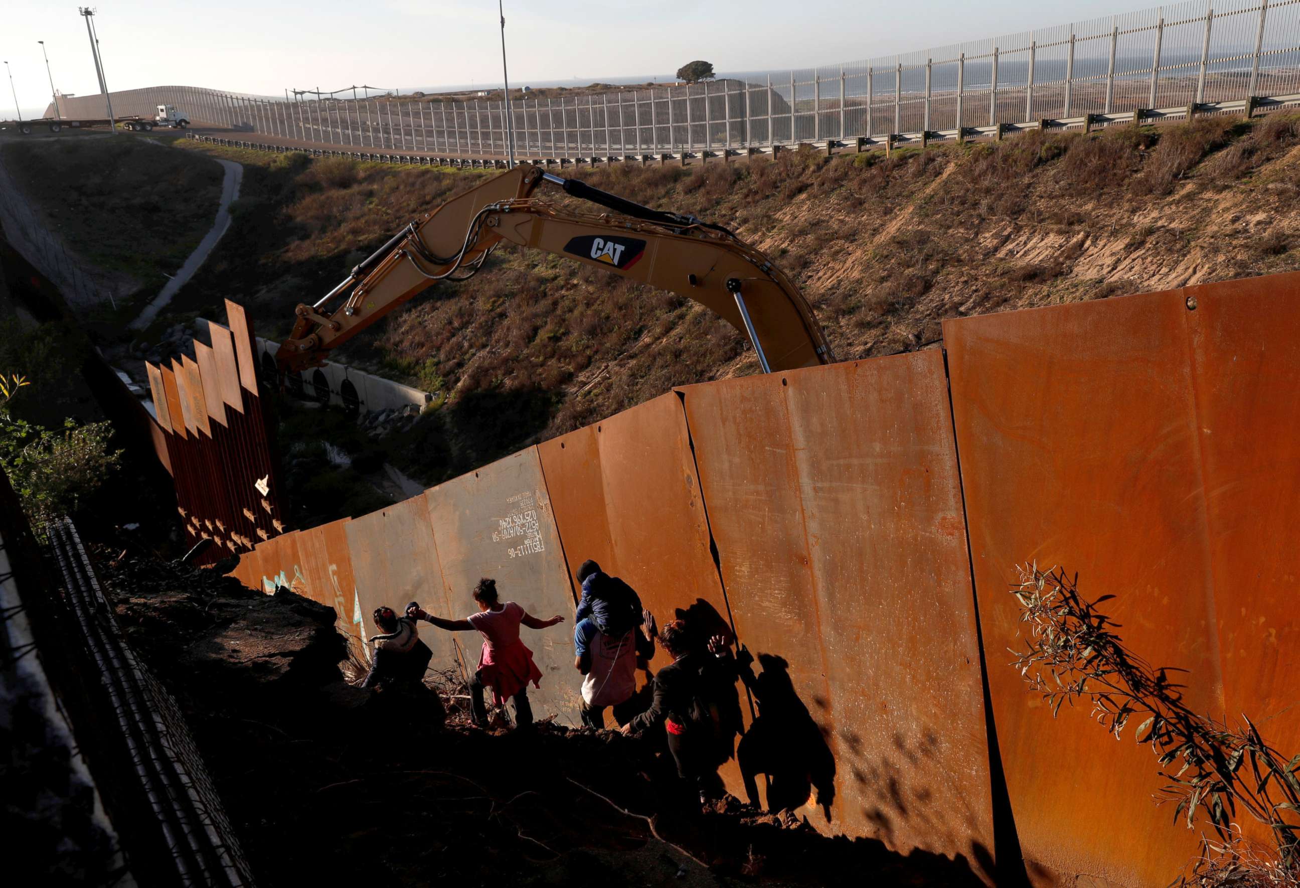 PHOTO: Migrants, part of a caravan of thousands from Central America trying to reach the U.S., climb down a steep hill after giving up on trying to climb the border wall into the U.S. from Tijuana, Mexico, Dec. 13, 2018.