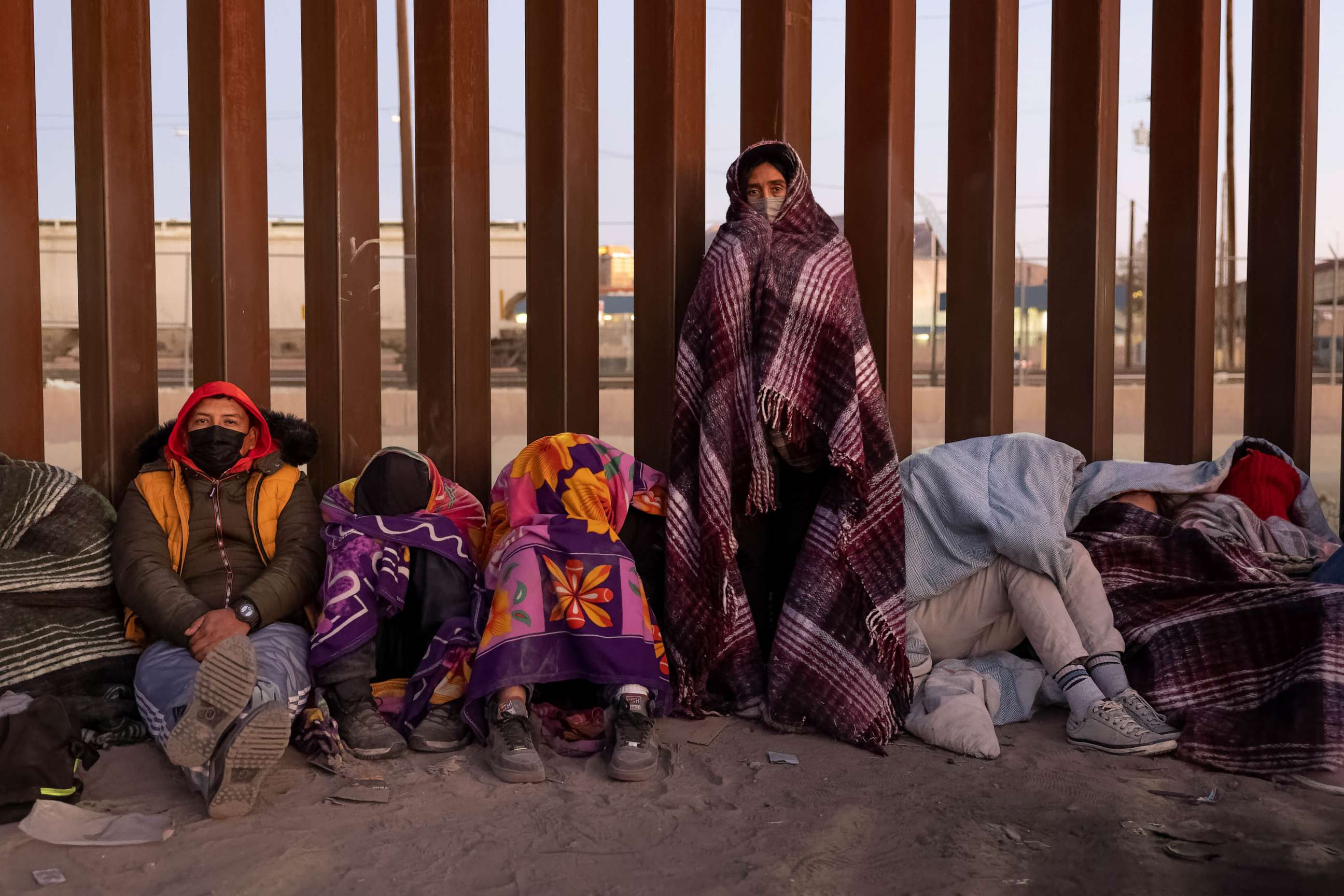 PHOTO: Immigrants bundle up against the cold after spending the night outside along the U.S.-Mexico border fence on Dec. 22, 2022, in El Paso, Texas.