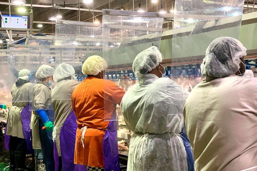PHOTO: In this April 2020, photo provided by Tyson Foods, workers wear protective masks and stand between plastic dividers at the company's Camilla, Georgia poultry processing plant.