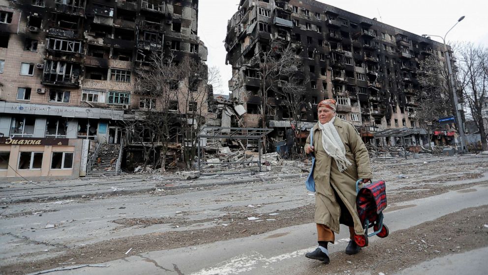 PHOTO: A woman walks along a street near an apartment building destroyed during Ukraine-Russia conflict in the southern port city of Mariupol, Ukraine, April 14, 2022. 