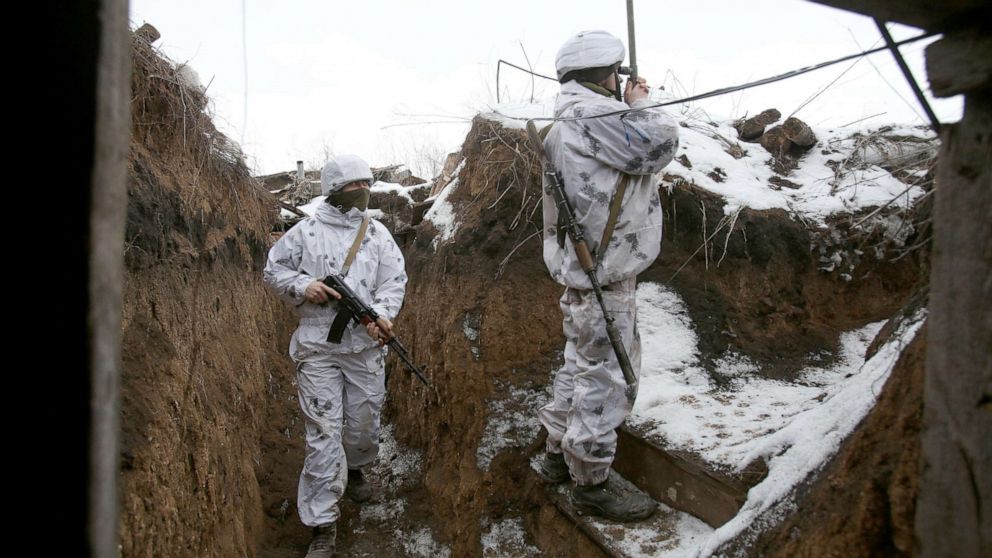 PHOTO: An Ukrainian soldier watches through spyglass as other one stands on guard near in a trench on the frontline with the Russia-backed separatists in the Donetsk region of Ukraine, Feb. 1, 2022.