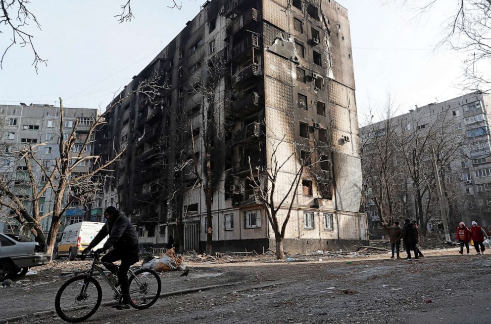 PHOTO: A local resident rides a bicycle past an apartment building damaged during Ukraine-Russia conflict in the besieged southern port city of Mariupol, Ukraine, on March 31, 2022.