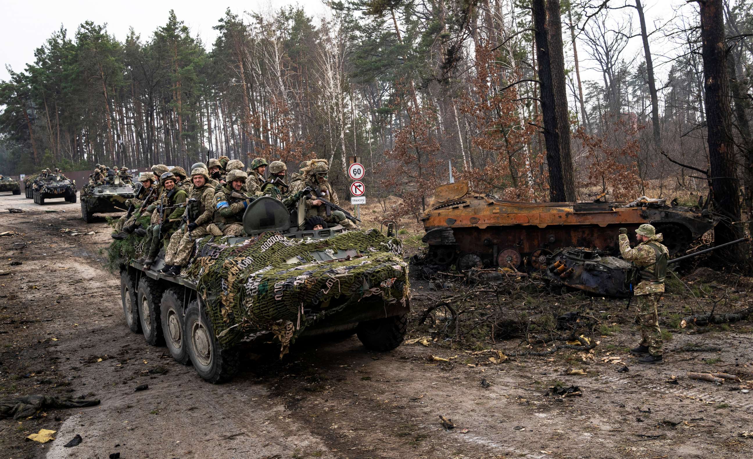 PHOTO: Ukrainian soldiers pass on top of armored vehicles next to a destroyed Russian tank in the outskirts of Kyiv, Ukraine, on March 31, 2022.