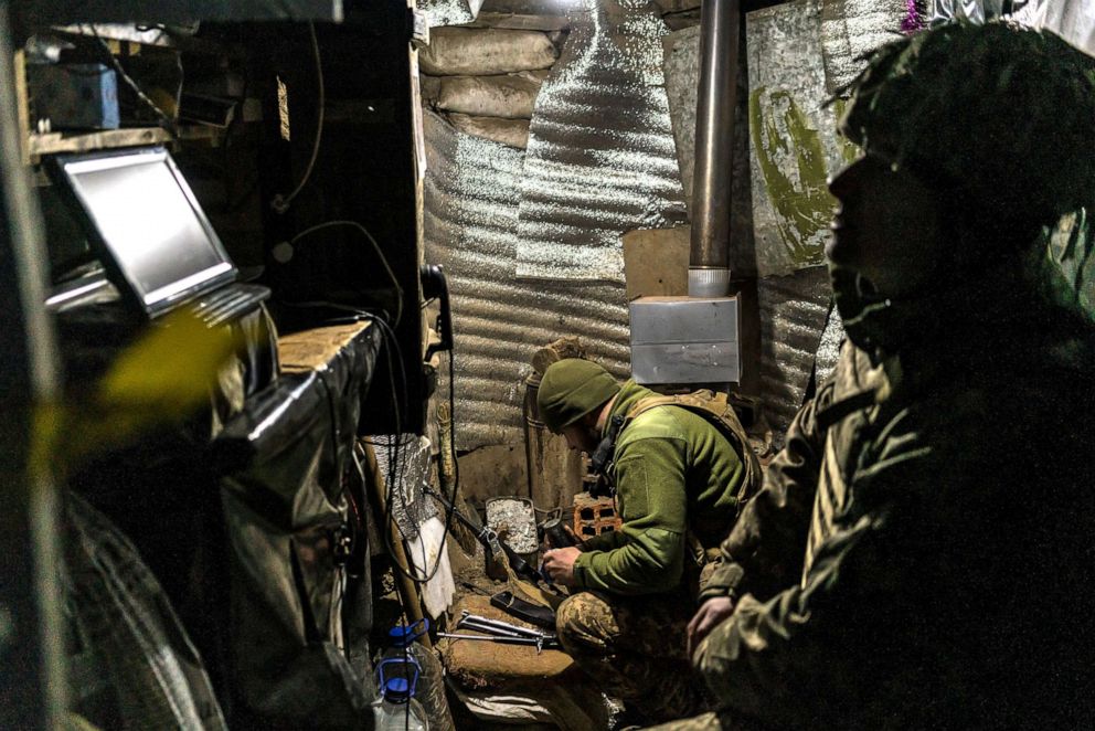 PHOTO: An Ukrainian soldier cleans his weapon as another relaxes in a small bunker near the front line on Jan. 17, 2022 in the village of New York, formerly known as Novhorodske, Ukraine.