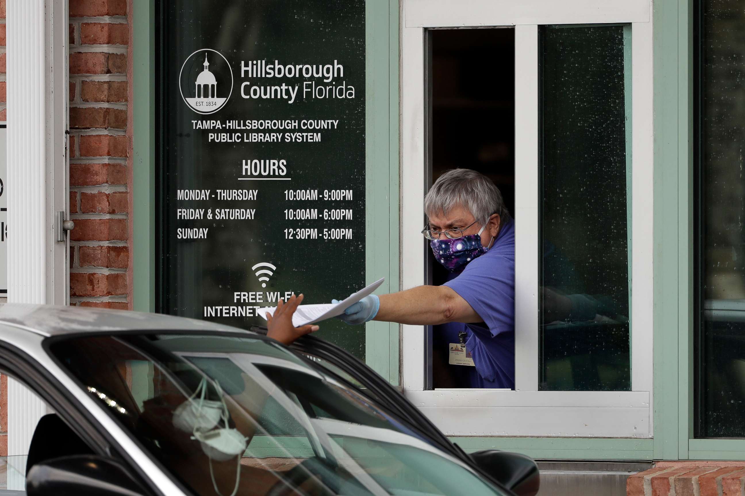 PHOTO: Hillsborough County Library Service employee Stephen Duran wears a mask and gloves to protect himself from the coronavirus outbreak as he hands out unemployment paperwork Tuesday, April 14, 2020, at a public library in Tampa, Fla.