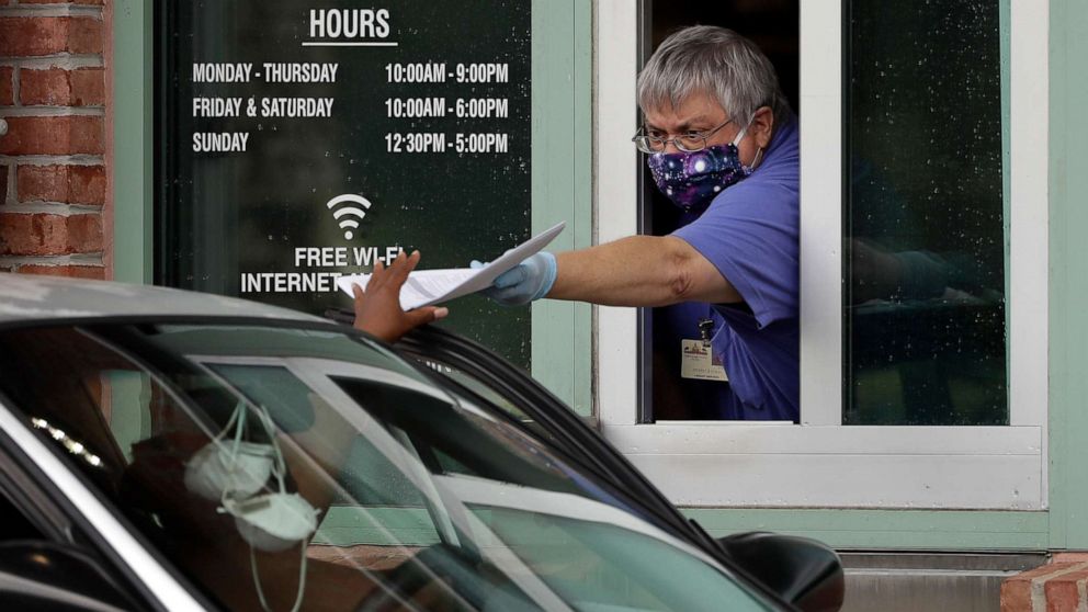 PHOTO: Hillsborough County Library Service employee Stephen Duran wears a mask and gloves to protect himself from the coronavirus outbreak as he hands out unemployment paperwork Tuesday, April 14, 2020, at a public library in Tampa, Fla.