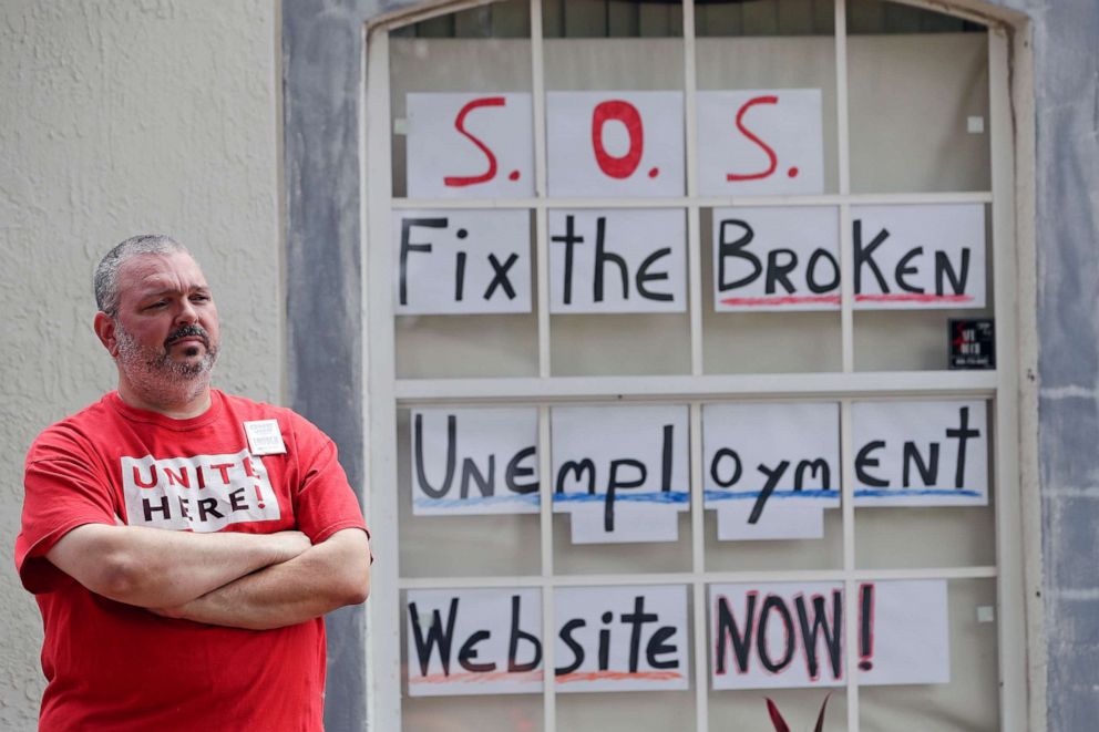 PHOTO: Hew Kowalewski, a furloughed employee of Disney World stands next to window of his home Monday, April 13, 2020, in Kissimmee, Fla.