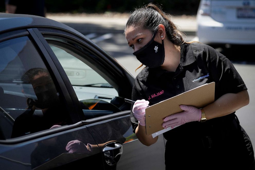 PHOTO: Jennifer Majano helps an job seeker fill out an application at a drive up job fair for Allied Universal, May 6, 2020, in Gardena, Calif.