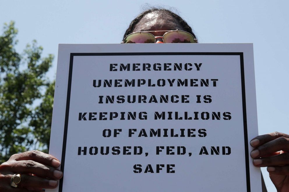 PHOTO: A person holds a placard as protesters temporarily block the street to Senate Majority Leader Mitch McConnell's house with a live band on a flatbed truck, demanding the extension of COVID-19-related unemployment aid, in Washington, July 22, 2020.