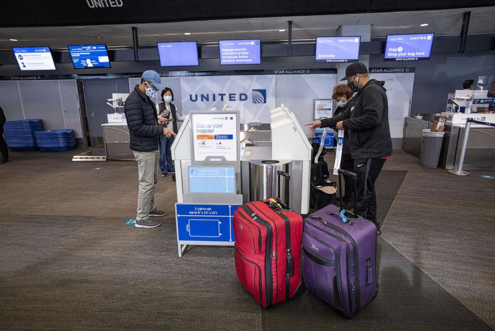 PHOTO: Travelers wearing protective masks use automated kiosks at the United Airlines check-in area at San Francisco International Airport on Jan. 19, 2021.