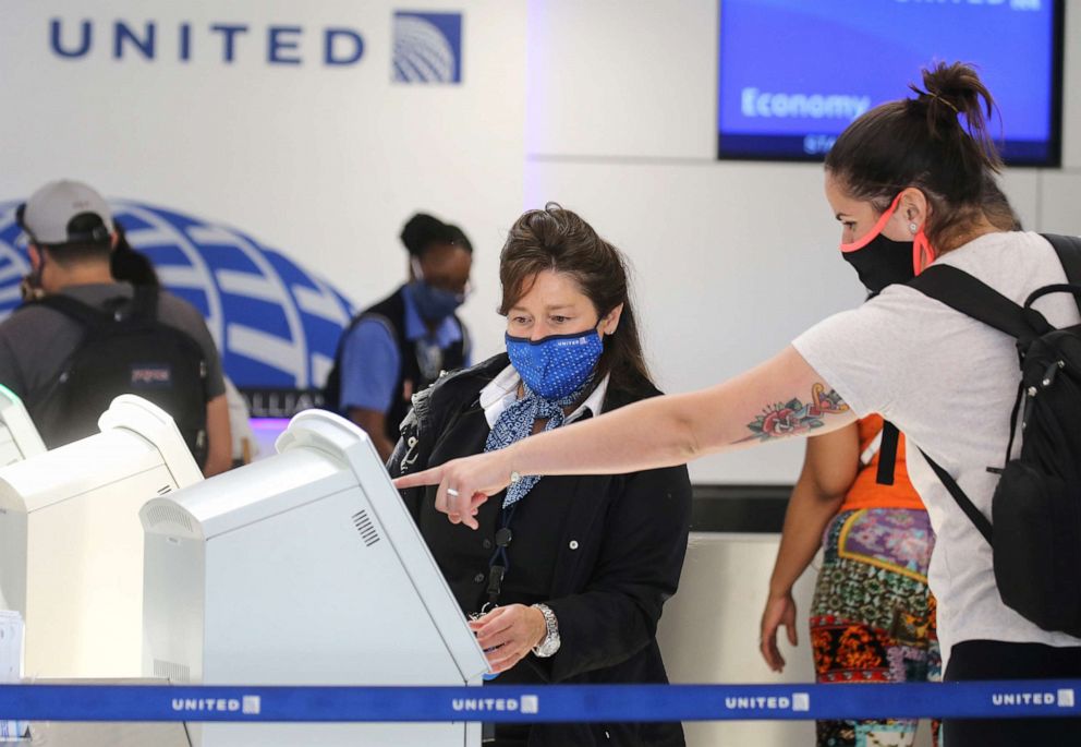 PHOTO: A United Airlines employee wears a required face covering along with a passenger at check-in at Los Angeles International Airport amid the COVID-19 pandemic, Oct. 1, 2020, in Los Angeles.