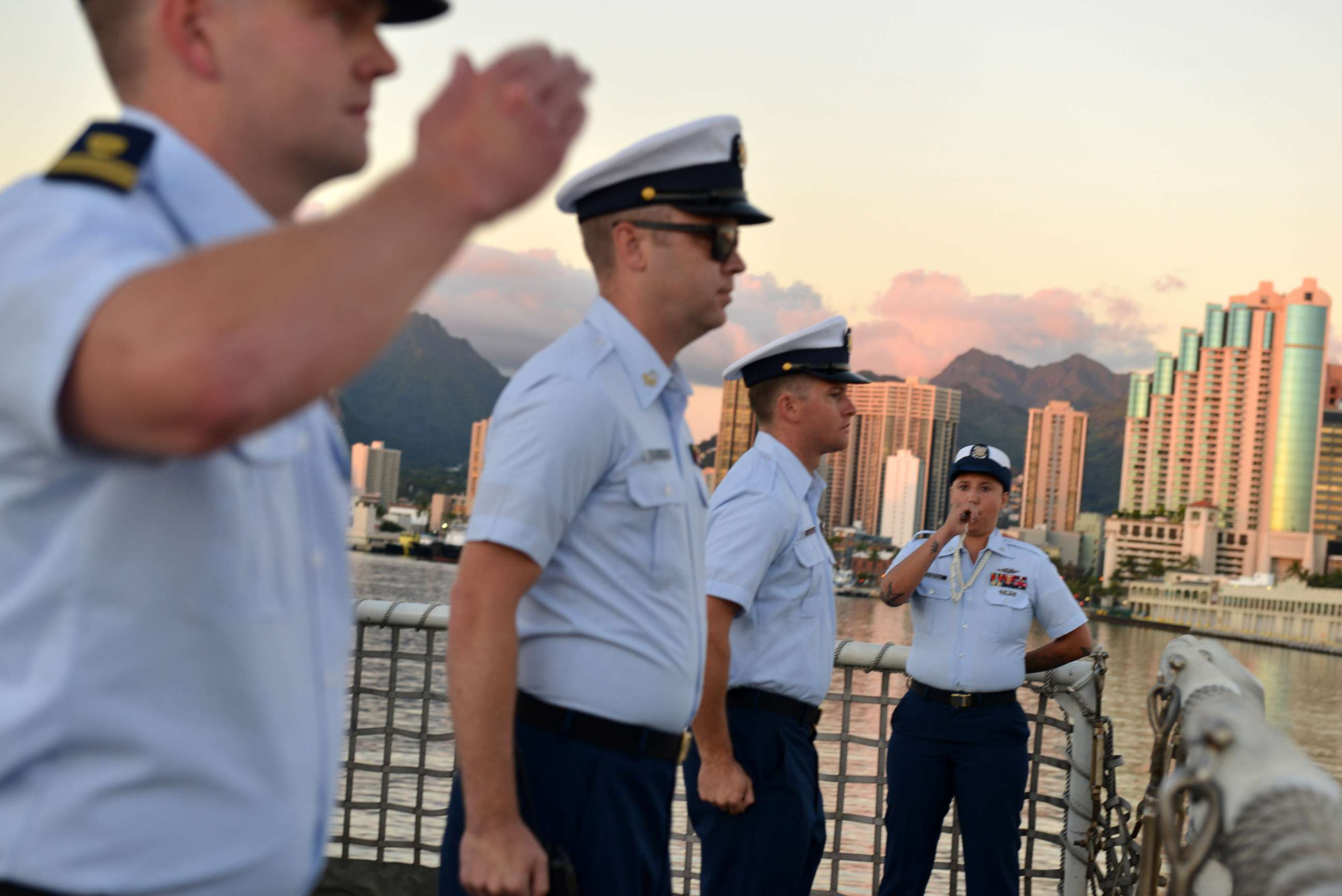 PHOTO: Petty Officer 3rd Class Bianca Valenzuela pipes colors using a boatswains pipe during a ceremony aboard the Coast Guard Cutter Sherman the evening before the cutter is scheduled to be decommissioned in Honolulu, Mar. 28, 2018.