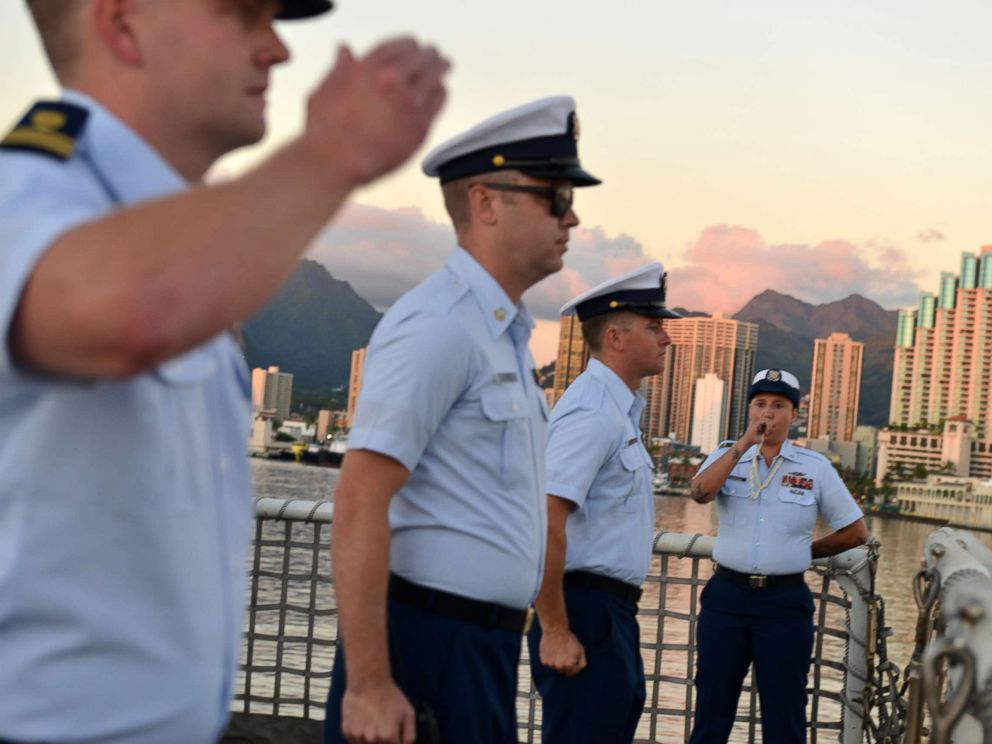 PHOTO: Petty Officer 3rd Class Bianca Valenzuela pipes colors using a boatswains pipe during a ceremony aboard the Coast Guard Cutter Sherman the evening before the cutter is scheduled to be decommissioned in Honolulu, Mar. 28, 2018.