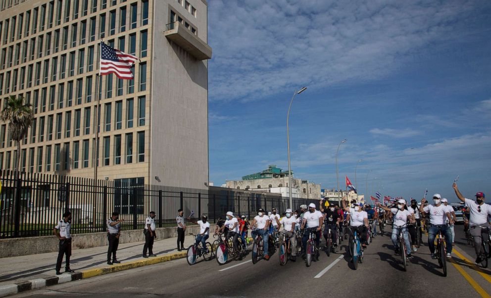 PHOTO: Supporters of the Cuban government carry Cuban flags as they ride bikes past the US embassy in Havana, Cuba, Aug. 5, 2021.