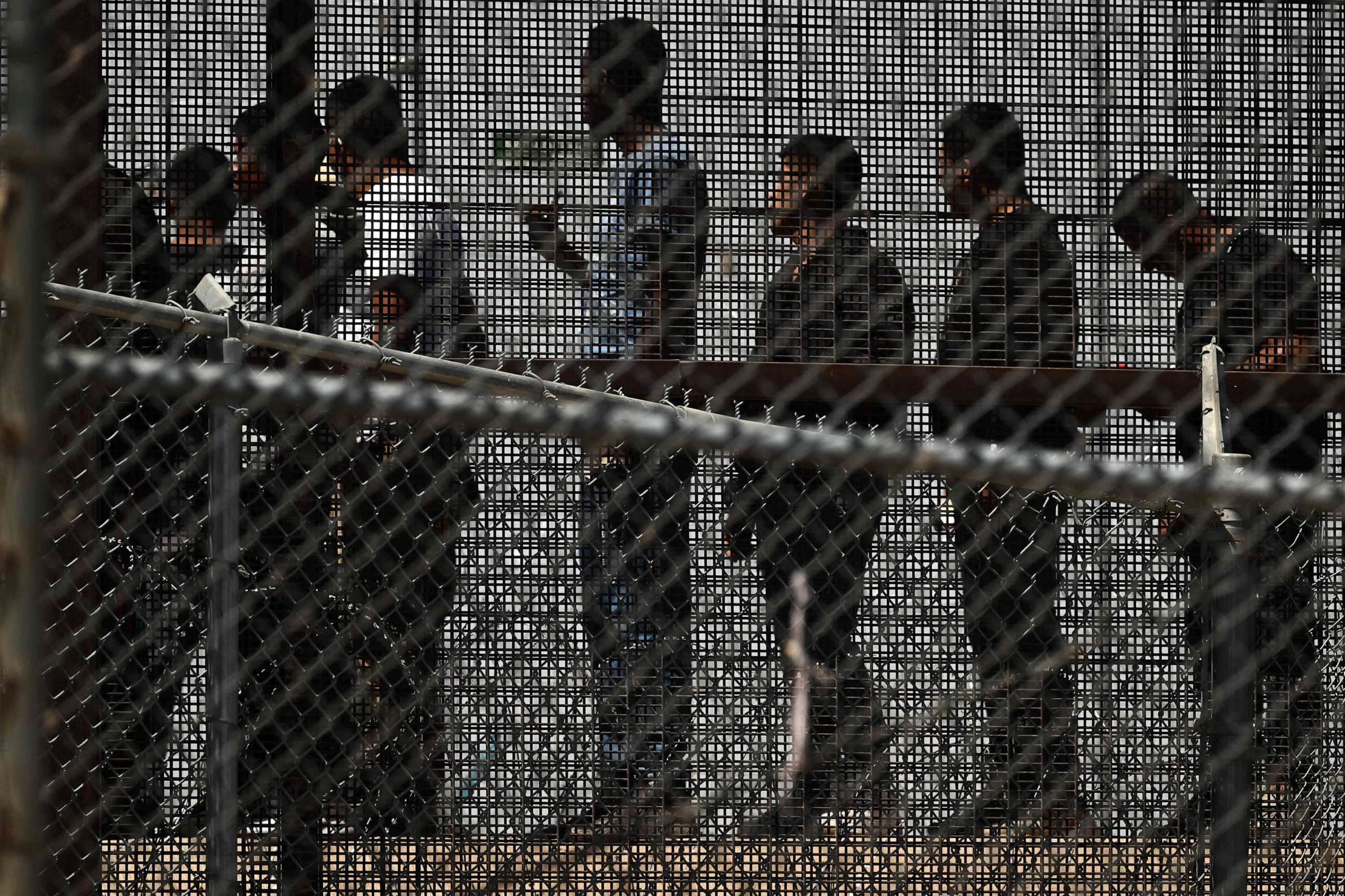 PHOTO: Migrants wait in along the border wall to board a bus after surrendering to US Customs and Border Protection (CBP) Border Patrol agents for immigration and asylum claim processing on the US-Mexico border in El Paso, Texas, May 12, 2023.