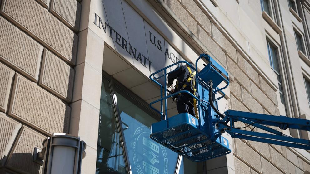 PHOTO: A worker removes the U.S. Agency for International Development sign on their headquarters on Feb. 07, 2025 in Washington, DC.
