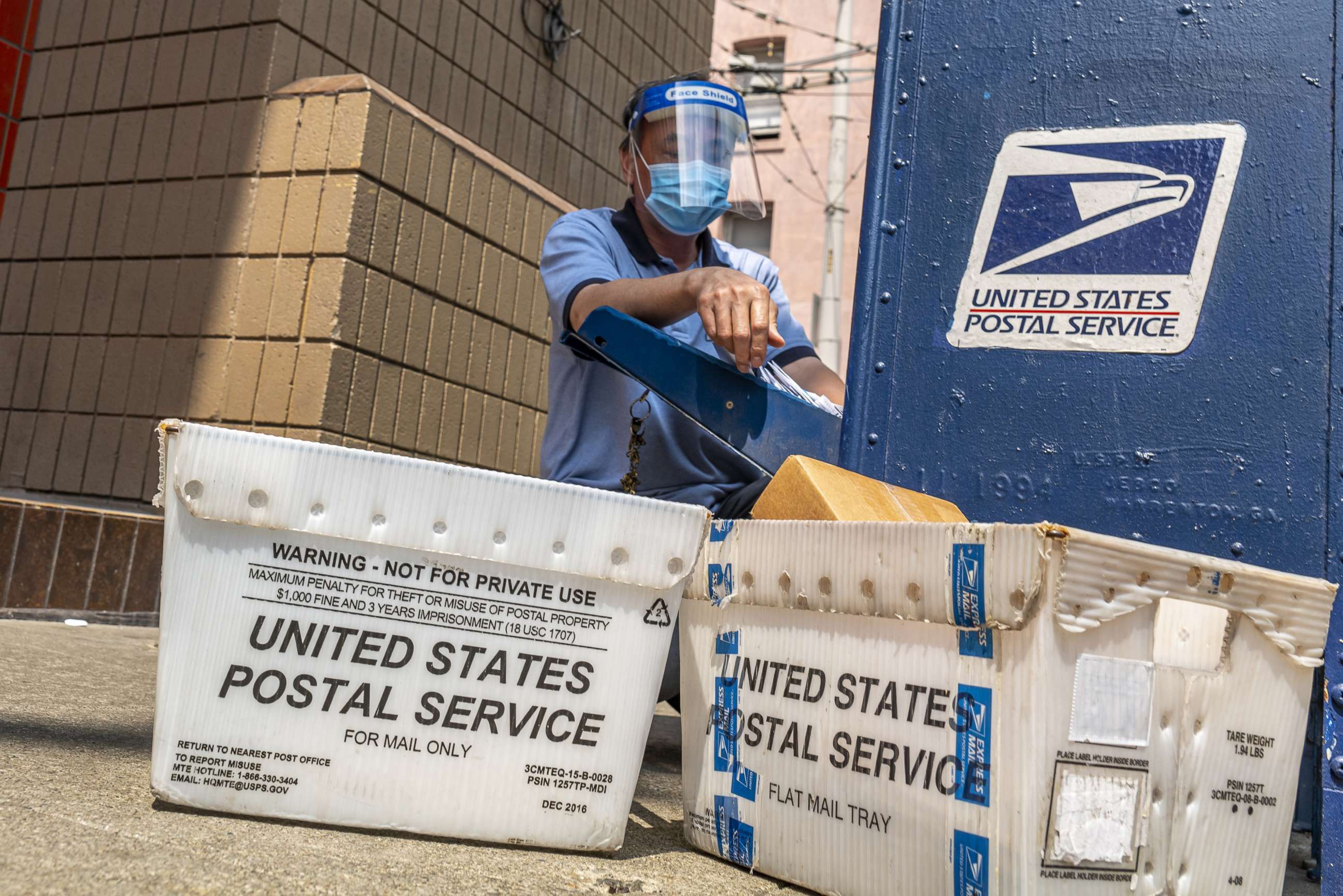 PHOTO: A U.S. Postal Service worker wearing a protective mask and face shield removes mail from a dropbox in San Francisco, Calif., Aug. 17, 2020. 