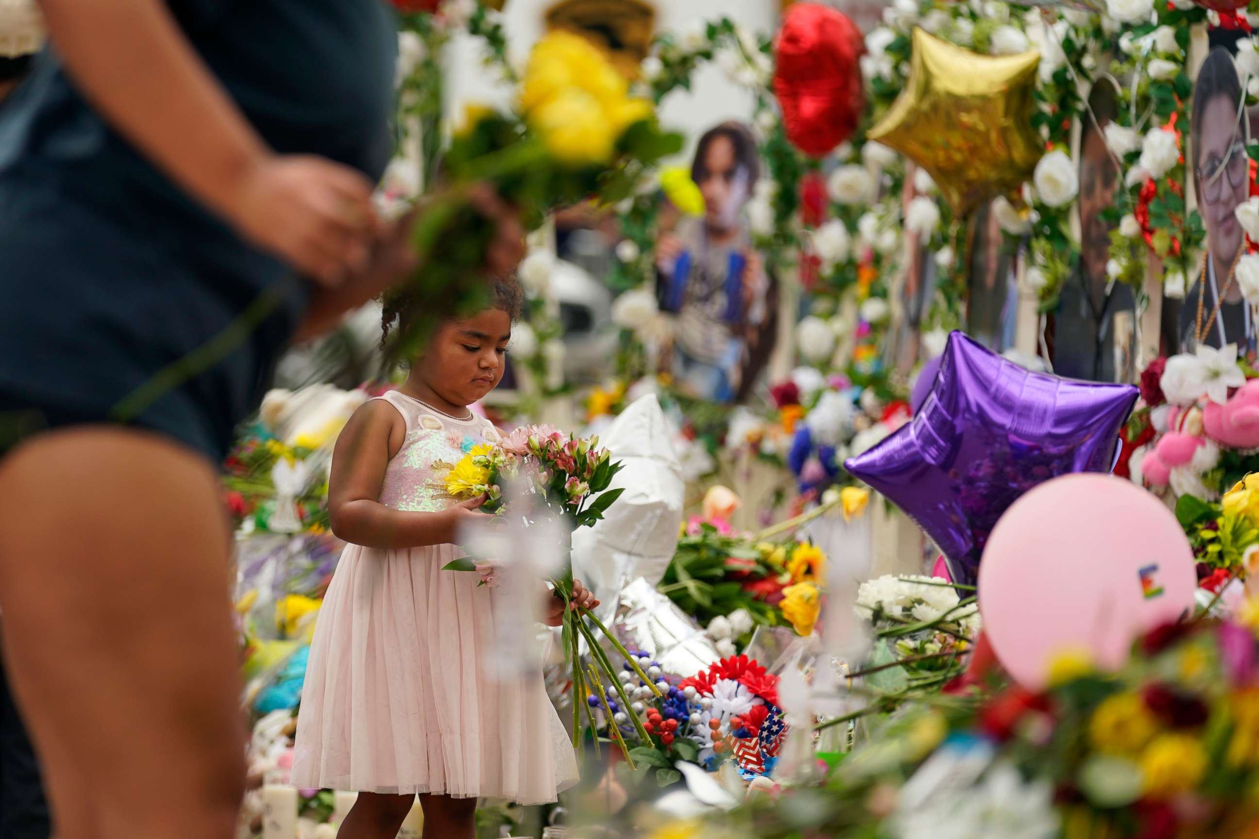 PHOTO: A young visitor brings flowers to a memorial as for the victims killed in last week's Robb Elementary School shooting, May 31, 2022, in Uvalde, Texas.