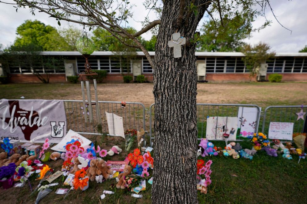 PHOTO: A cross hangs on a tree at Robb Elementary School where a memorial has been created to honor the victims killed in the recent school shooting, June 3, 2022, in Uvalde, Texas.