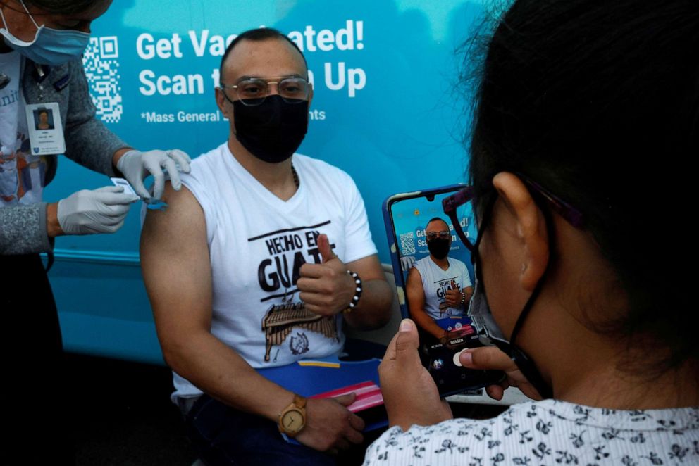 PHOTO: Sofia Palacios, 8, takes photographs of her father Alexander getting his coronavirus disease (COVID-19) vaccine, after she received the vaccine herself, at a clinic at La Colaborativa, in Chelsea, Massachusetts, Nov. 9, 2021.