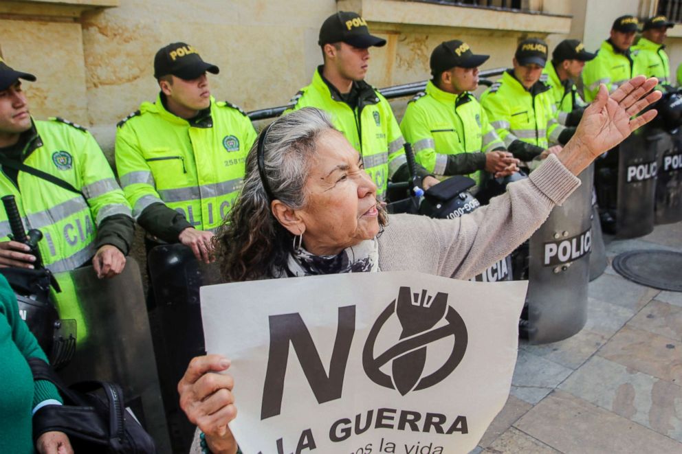 PHOTO: Police forces stand behind an activist holding a sign that reads "No to the war in Venezuela, Let's defend life," during a demonstration outside Colombia's Foreign Ministry in Bogota, Feb. 25, 2019.