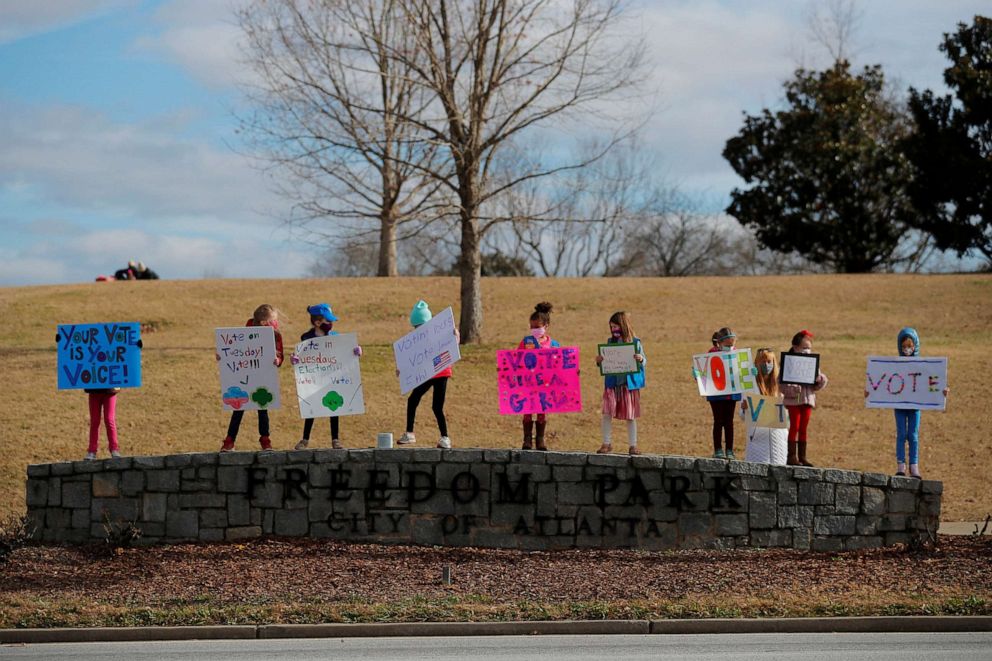 PHOTO: Girl Scouts from Troops 20777 and 18120 hold signs urging residents to vote in the runoff election for both of Georgia's Senate seats in Atlanta, Jan. 3, 2021.