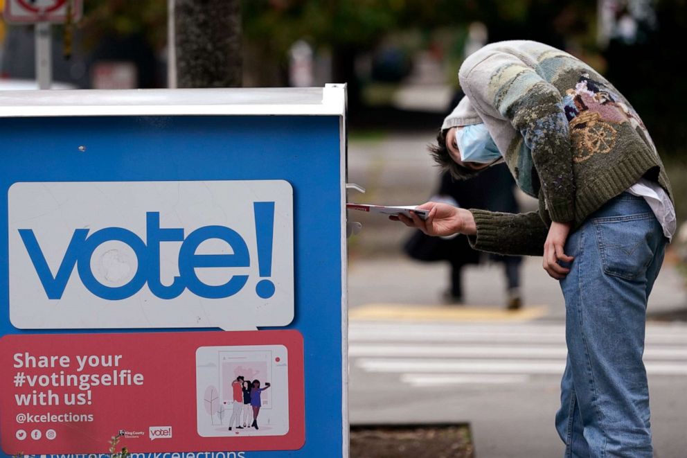 PHOTO: A voter turns sideways as he eyes the opening of a ballot drop box before placing his ballot inside it Wednesday, Oct. 28, 2020, in Seattle.