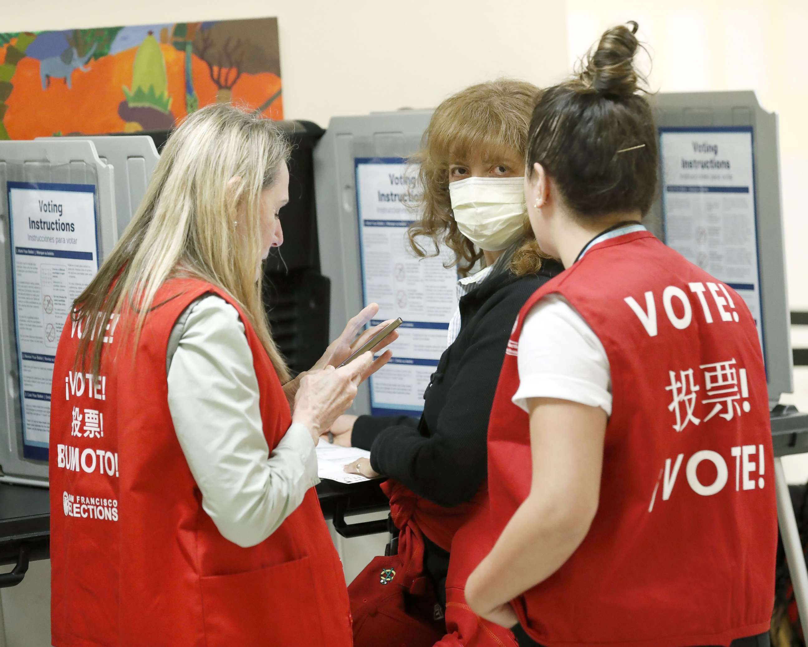 PHOTO: Poll workers speak to a woman wearing a face mask in a polling site at San Francisco City Hall on Super Tuesday, March 3, 2020, in San Francisco.