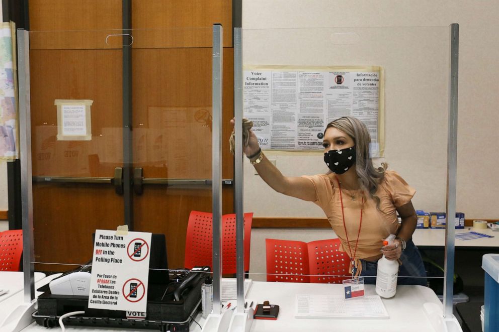 PHOTO: Cameron County early voting clerk Crystal Garcia sanitizes the plastic shields for the poll worker's station, Oct. 15, 2020, before the early voting polling location opens in Brownsville, Texas.