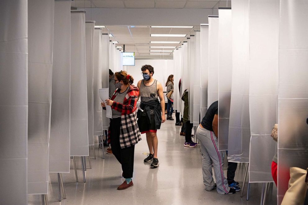 PHOTO: Residents of Cuyahoga county, separated by plastic due to health concerns amid the coronavirus pandemic, arrive to fill out paper ballots for early, in person voting at the board of elections office in downtown Cleveland, Oct. 16, 2020.