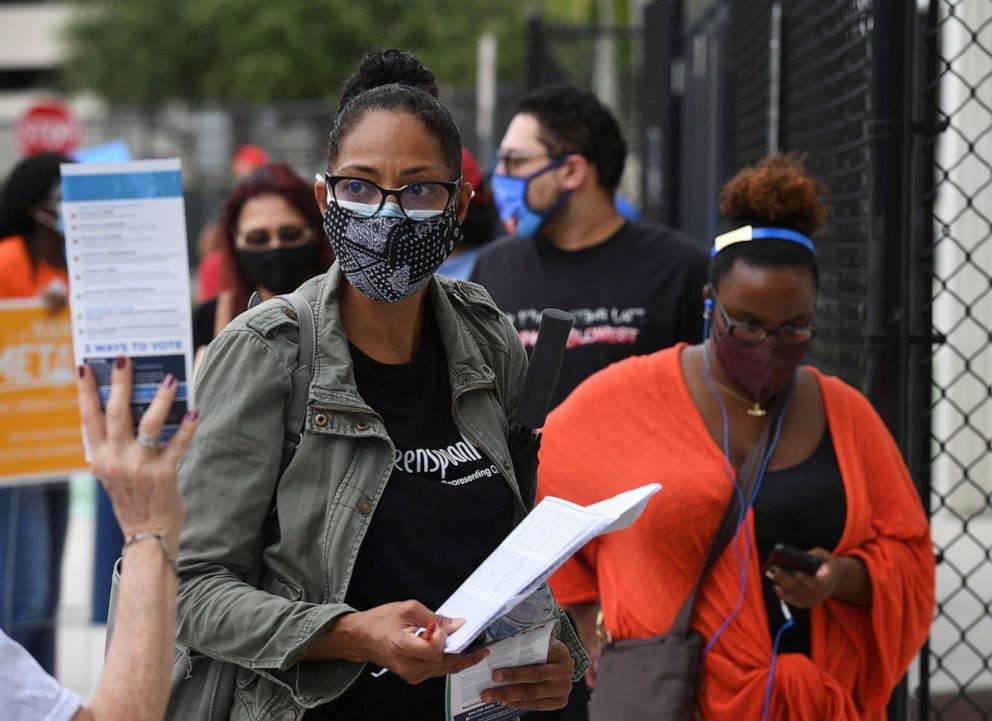 PHOTO: Voters are seen waiting in line to cast their ballots as Florida starts in person voting at the Northwest Regional Library during the 2020 Presidential Election on Oct. 19, 2020, in Coral Springs, Fla.