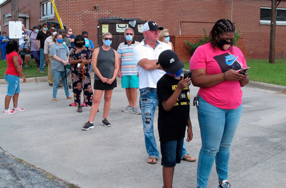PHOTO: Voters wearing masks wait in line to vote early outside the Chatham County Board of Elections office in Savannah, Ga., Oct. 14, 2020.
