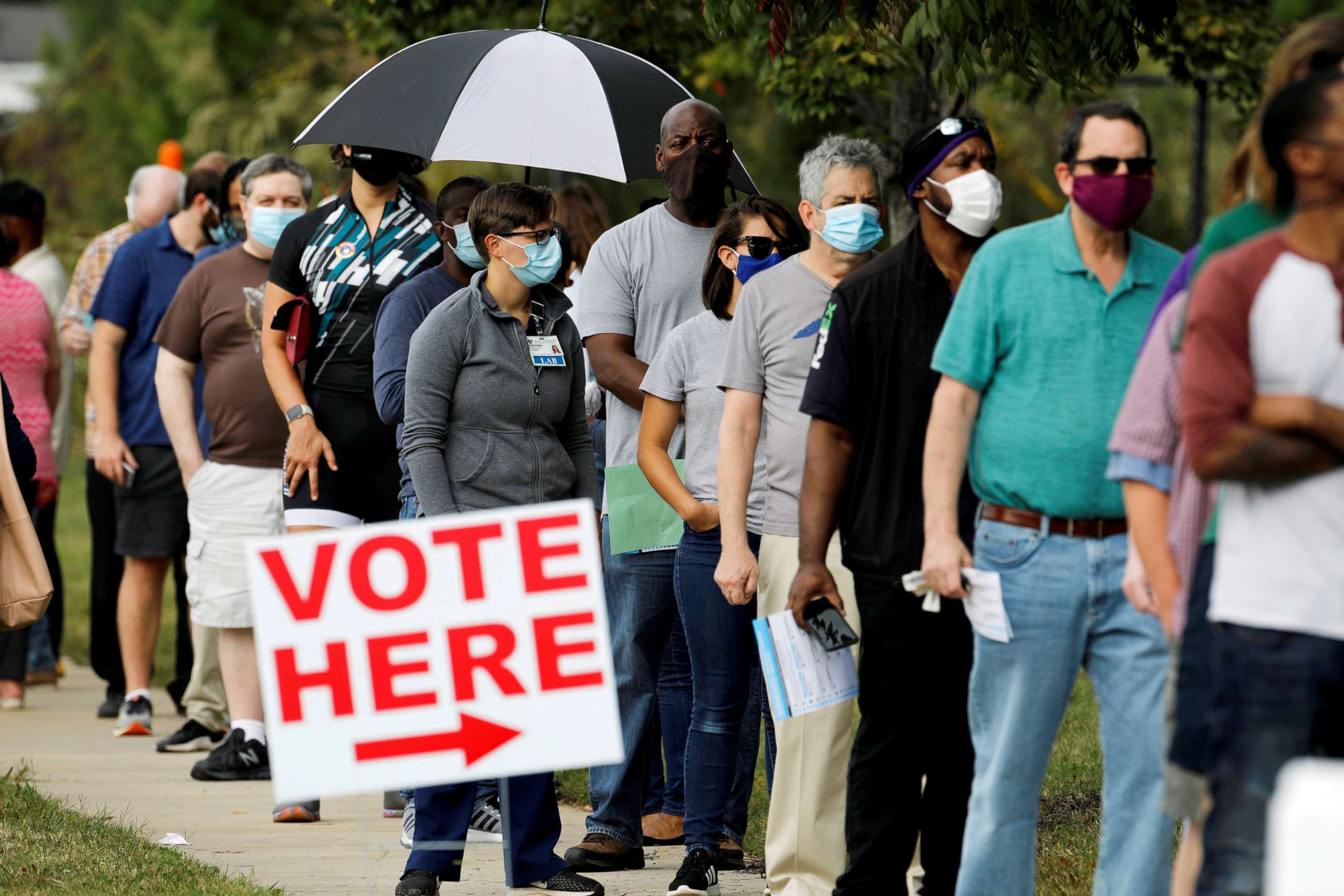 PHOTO: Voters wait in line to enter a polling place and cast their ballots on the first day of the state's in-person early voting for the general elections in Durham, North Carolina, Oct. 15, 2020.