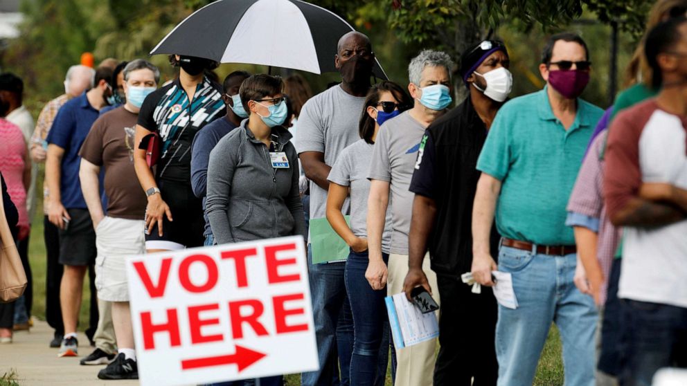 PHOTO: Voters wait in line to enter a polling place and cast their ballots on the first day of the state's in-person early voting for the general elections in Durham, North Carolina, Oct. 15, 2020.