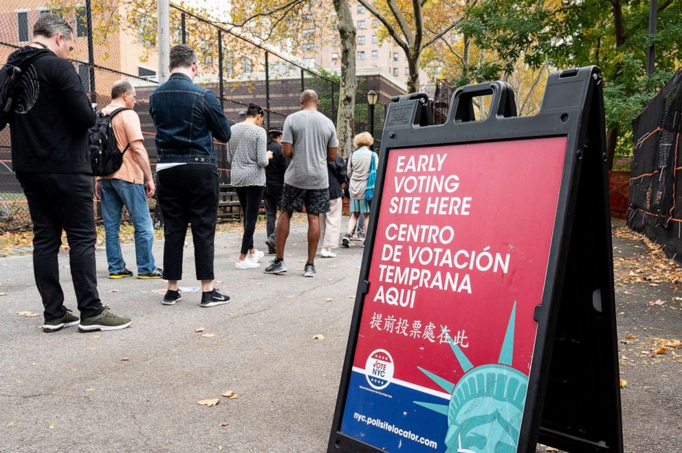 PHOTO: A sign advertises an early voting site as voters wait in a queue to enter West Side High School during early voting in New York City on Nov. 6, 2022.