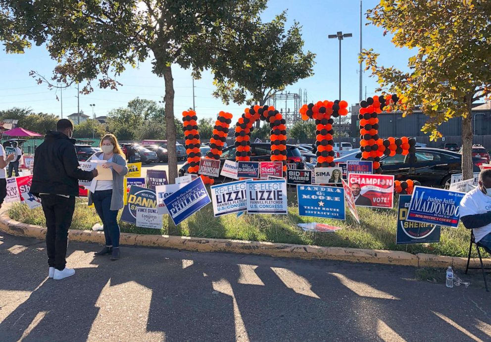 PHOTO: People speak with voters near signs outside of the Metropolitan Multi-Services Center of Montrose in Houston on the last day of early voting, Oct. 30, 2020. 