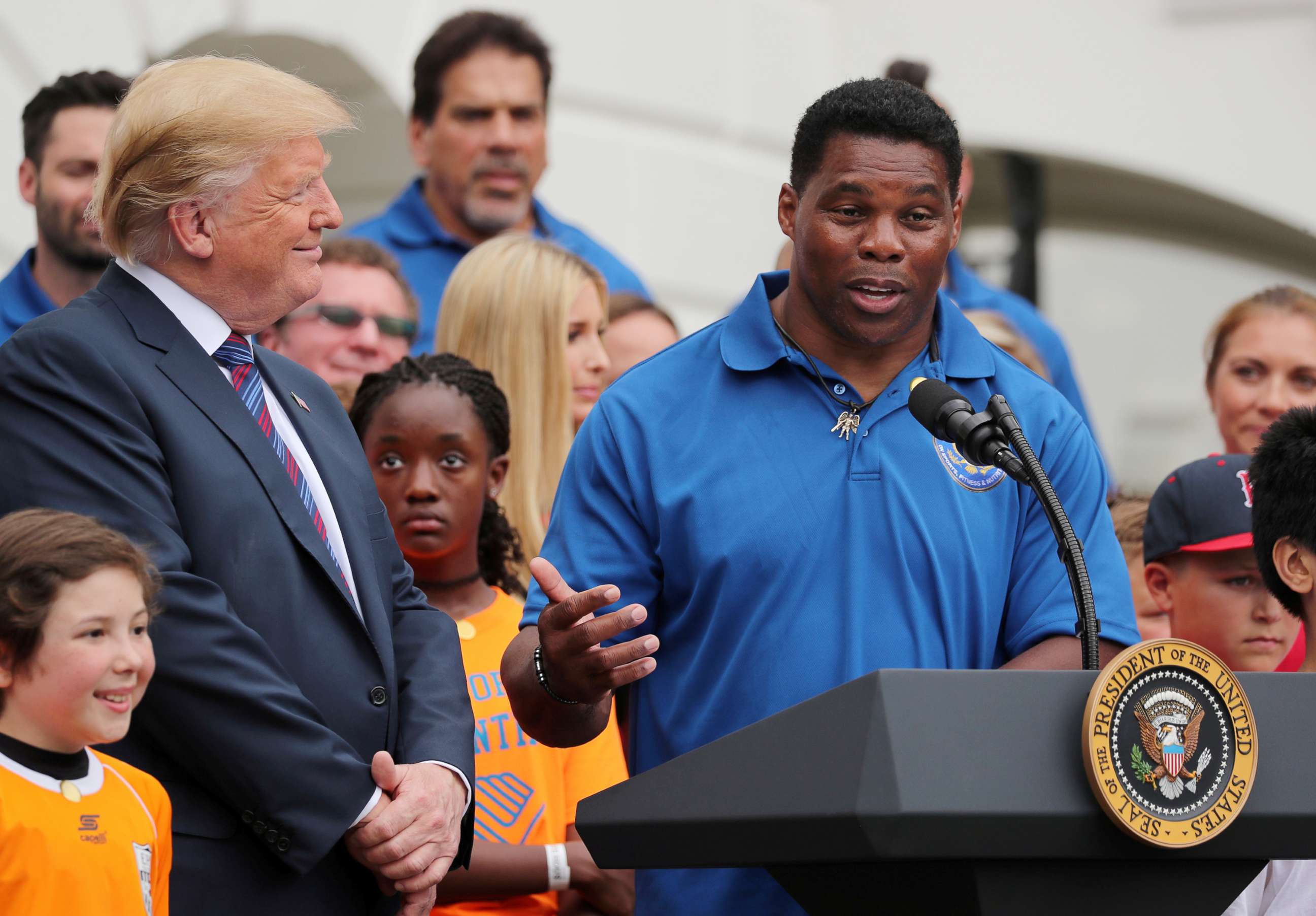PHOTO: In this May 30, 2018 file photo President Donald Trump listens to former NFL star Herschel Walker speak during the White House Sports and Fitness Day event on the South Lawn of the White House in Washington D.C.