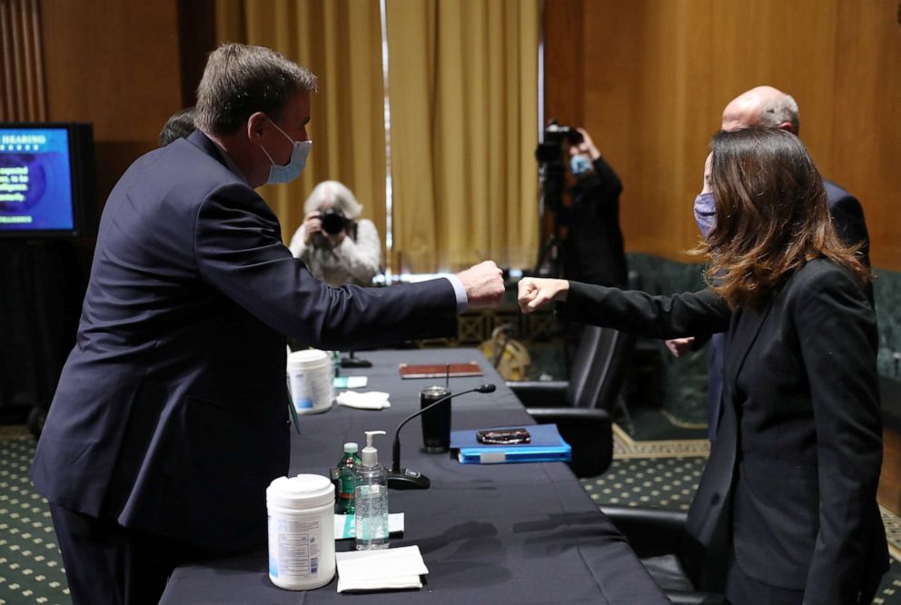 PHOTO: Avril Haines, right, bumps fists with Sen. Mark Warner before the start of the Senate Intelligence Committee confirmation hearing to be President-elect Joe Biden's pick for national intelligence director on Jan. 19, 2021, in Washington.