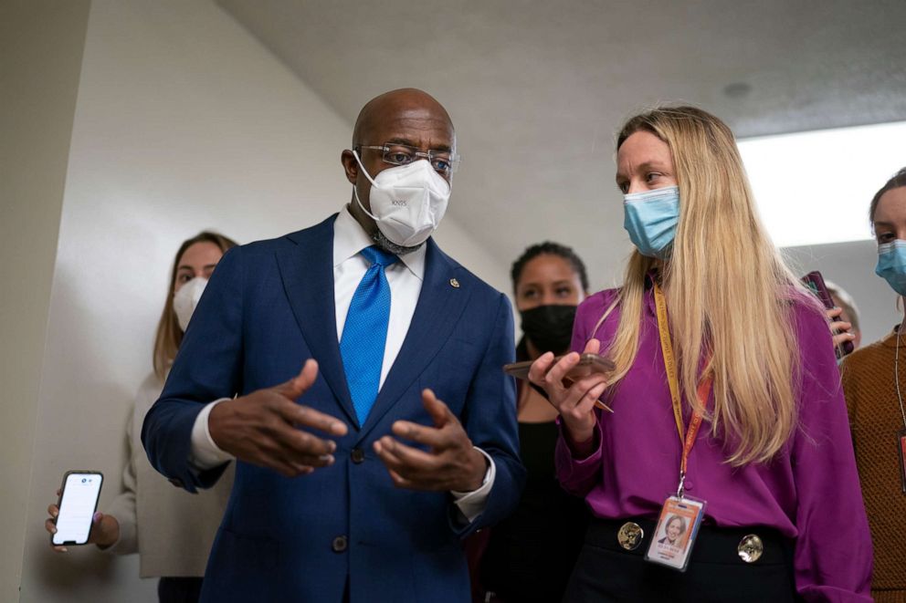 PHOTO: Sen. Raphael Warnock talks to reporters as he arrives for a vote while the Senate continues to grapple with end-of-year tasks and the future of the President's social and environmental spending bill, at the Capitol in Washington, Dec. 15, 2021.