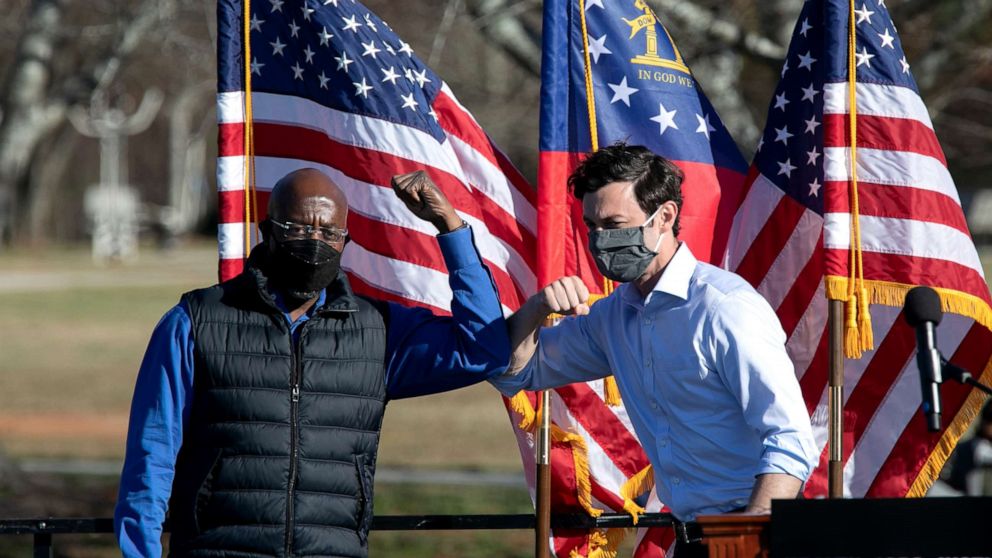 PHOTO: Democratic Senate candidates Raphael Warnock, left, and Jon Ossoff bump elbows during an outdoor drive-in rally, Dec. 5, 2020 in Conyers, Georgia.