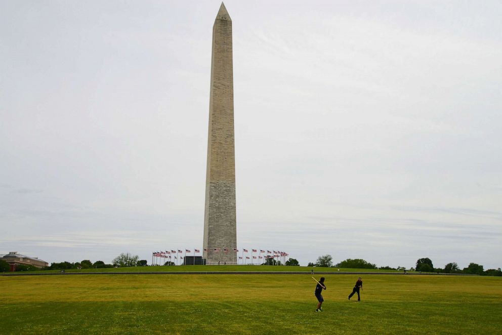 PHOTO: People play baseball on the empty, and closed, mall in front of the Washington Monument in Washington, D.C., May 19, 2020. 